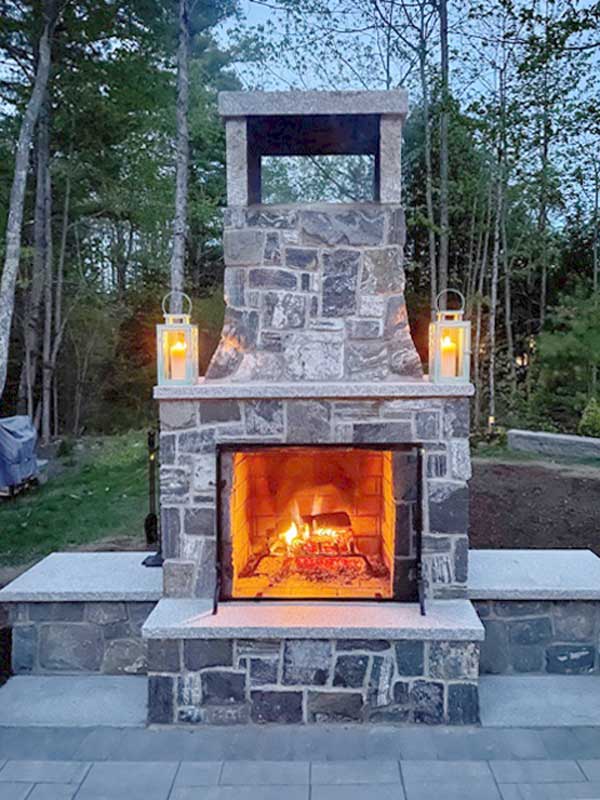 Outdoor fireplace showing fireplace screen in front of burning fire
