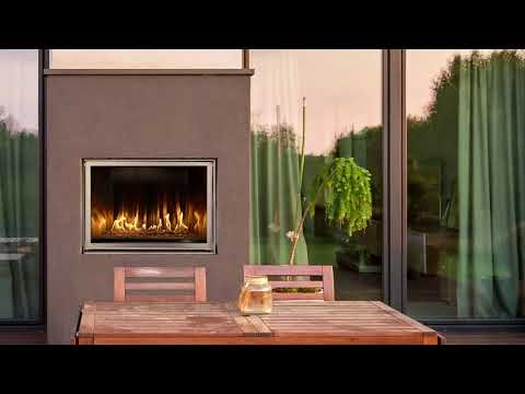 Video showing outdoor gas flame in outdoor area with table and chairs. Unot is built into a brown wall.