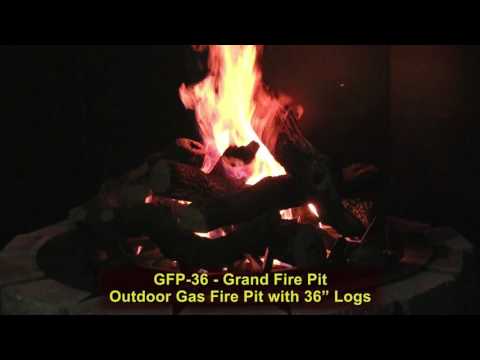 Grand Fire Pit with logs and lava rock and high gas flame against a black background
