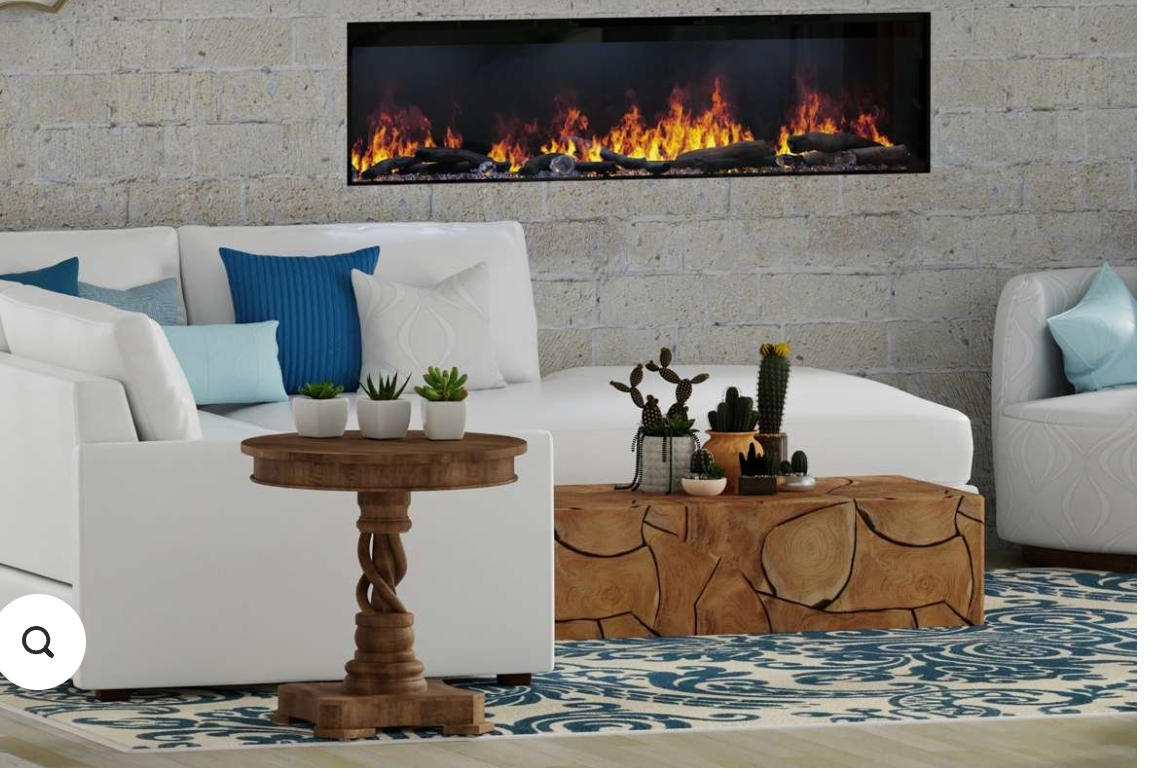 A modern living room scene featuring a long black linear fireplace mounted on a light gray brick wall above a white sectional sofa. The room includes a patterned blue and cream rug, a small wooden side table with potted plants, a carved wooden coffee table, and a matching armchair with a light blue pillow.