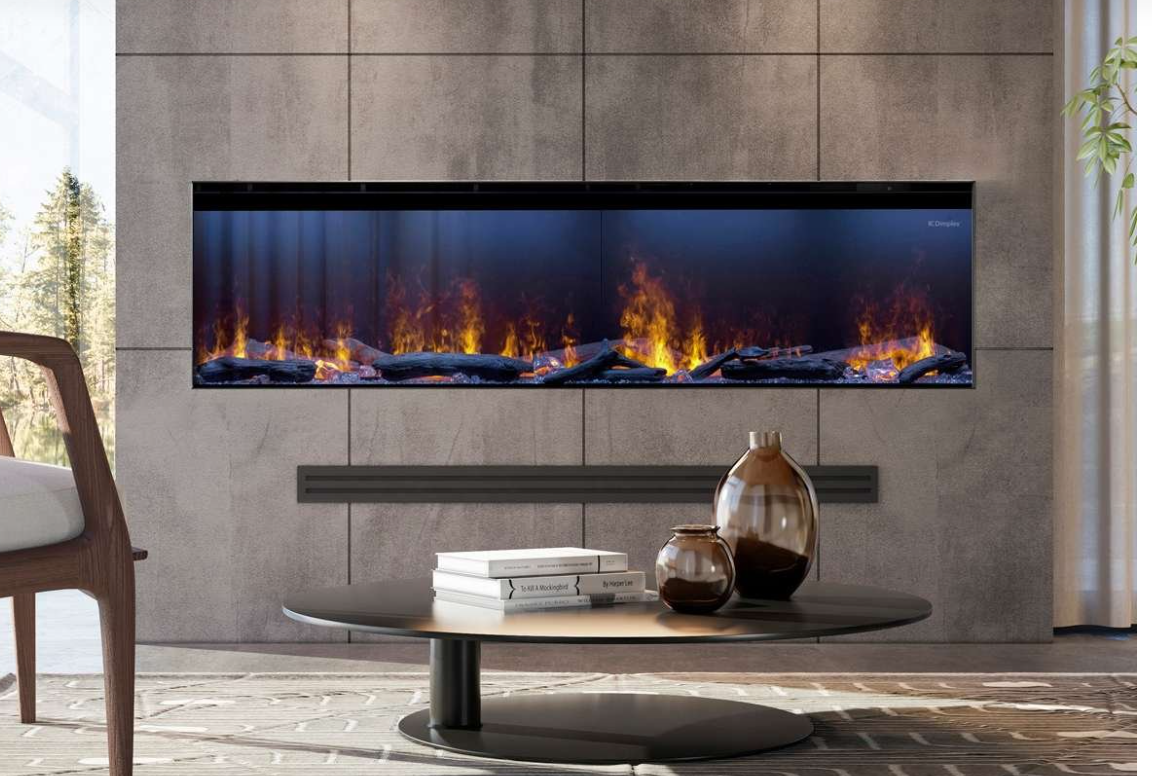 A long, narrow wall-mounted fireplace with a black frame and vivid orange and yellow flames over dark logs, set into a modern gray stone wall above a round coffee table with books and vases.