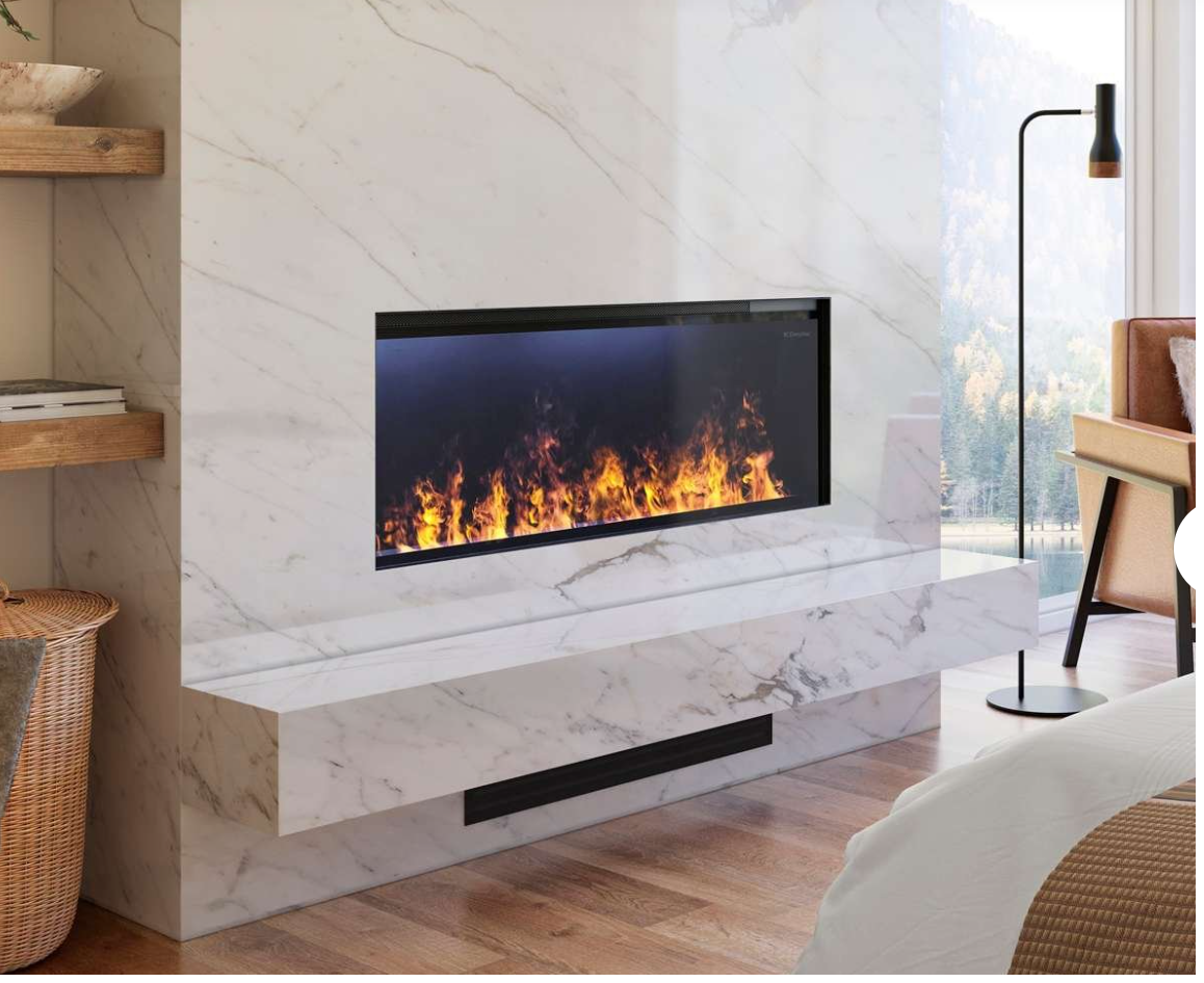 A modern linear electric fireplace with a black frame and realistic orange and yellow flames, set into a white marble fireplace wall with a floating mantel and shelf.