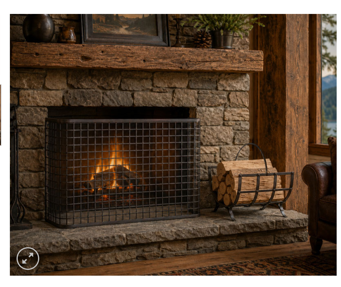 A black metal fireplace screen guard with a grid pattern, shown installed over a stone fireplace with a fire burning inside. The scene is set in a rustic cabin environment with a wood mantel, stone wall, a log basket, and a leather chair visible.