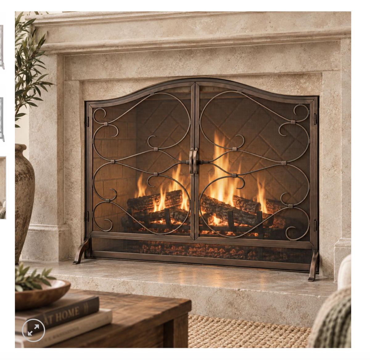 A decorative fireplace screen with ornate scrollwork in a dark metal finish, shown in front of a lit fireplace with wood logs. The screen is set within a stone fireplace mantel in a cozy living room setting.