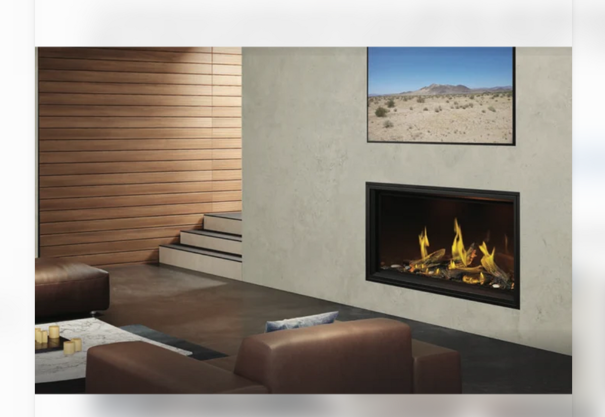 A modern gas fireplace with a black frame and realistic yellow flames, set into a textured beige wall in a contemporary living room. A framed desert landscape print hangs above the fireplace, and brown leather chairs and a wood-paneled wall are visible in the room.