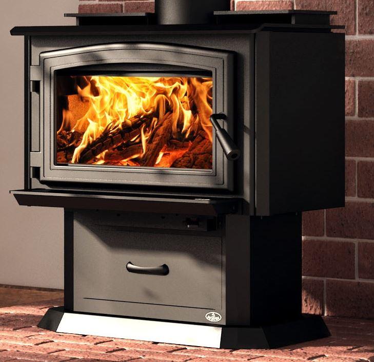 A black wood-burning stove with a glass door showing bright orange and yellow flames, set against a brick wall and brick floor.