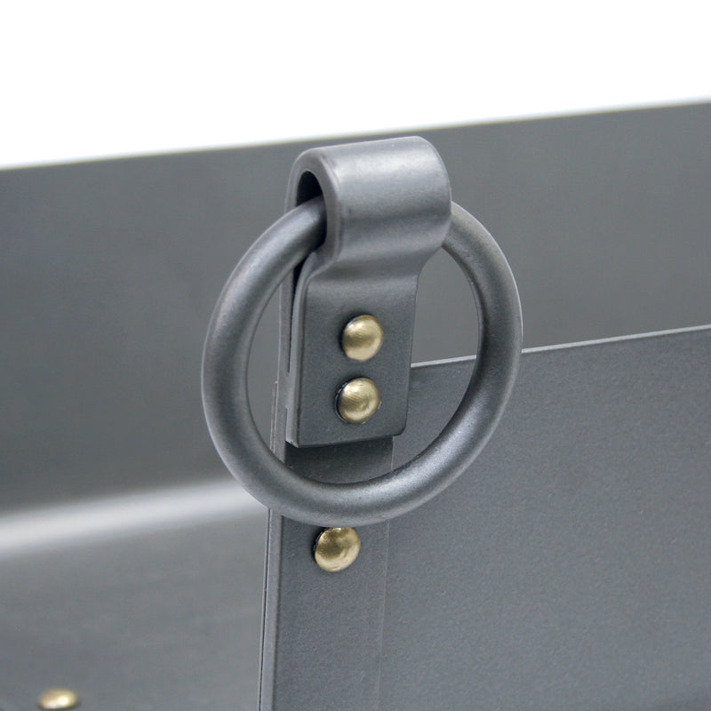 A close-up of a dark gray metal ring handle with brass-colored rivets, attached to a matching gray metal panel.