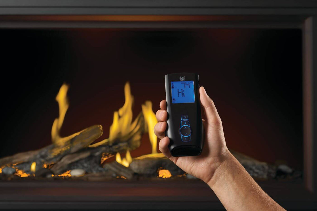 Hand holding a remote control in front of a lit fireplace