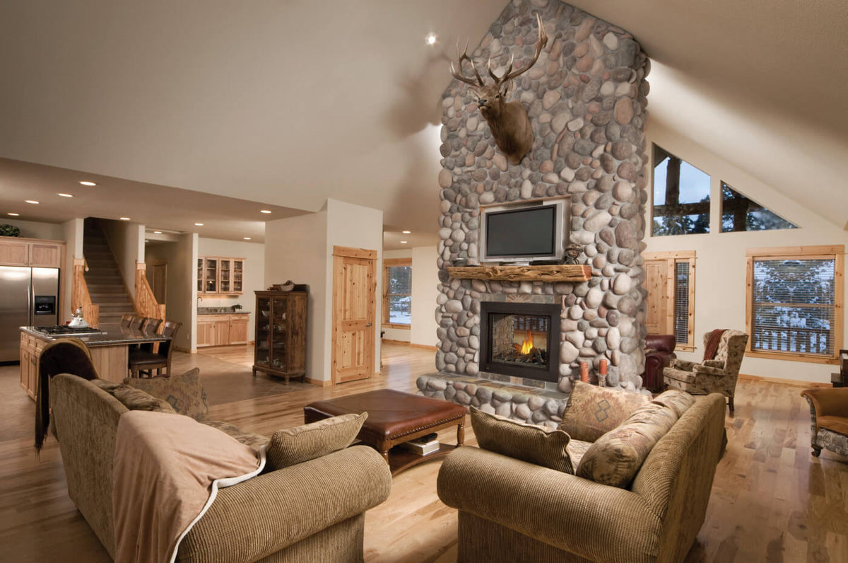 Living room with stone fireplace, couches, and a deer head mounted on the wall.